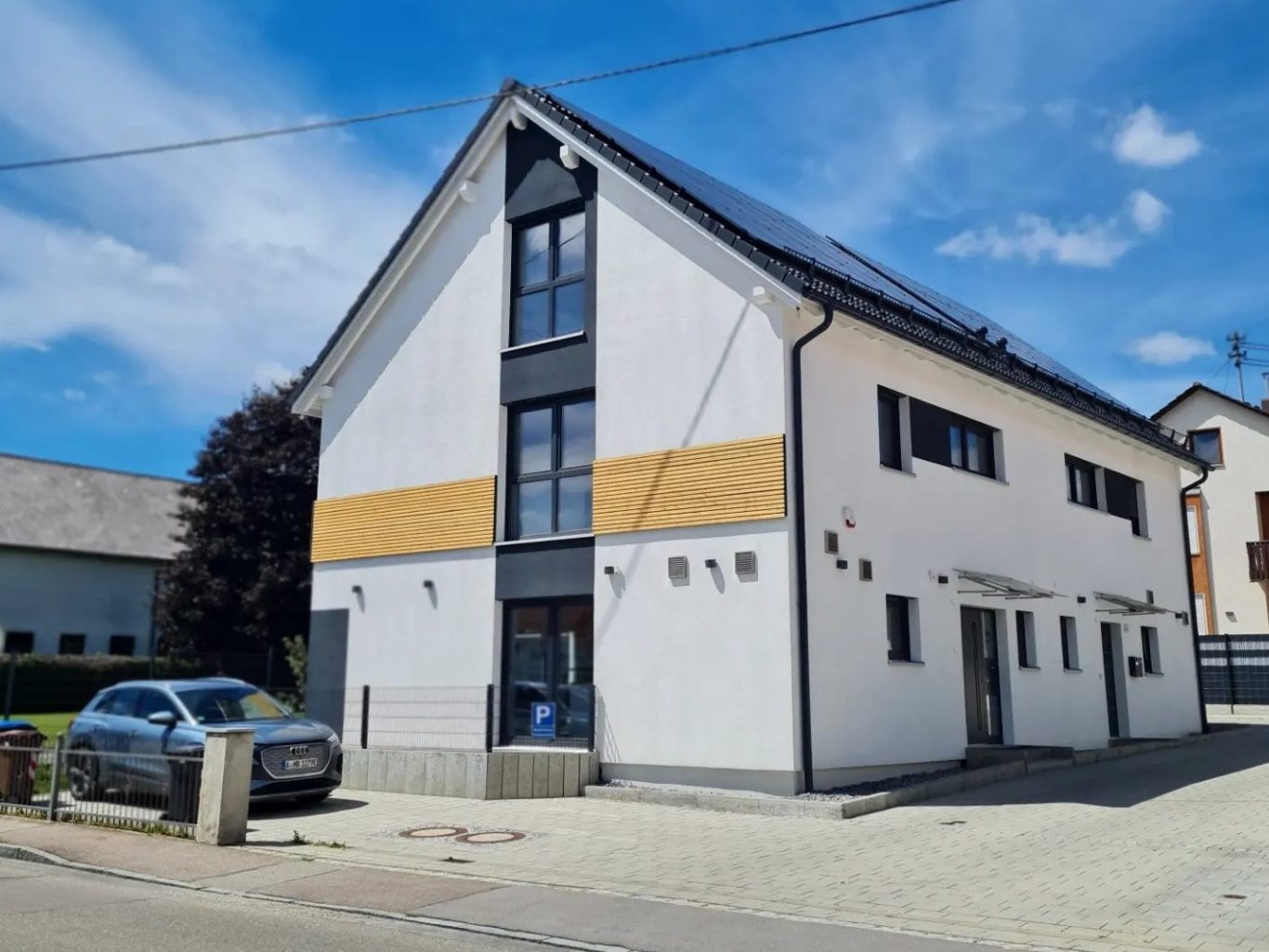 Modernes zweigeschossiges Gebäude mit weißer Fassade und Holzvertäfelung.