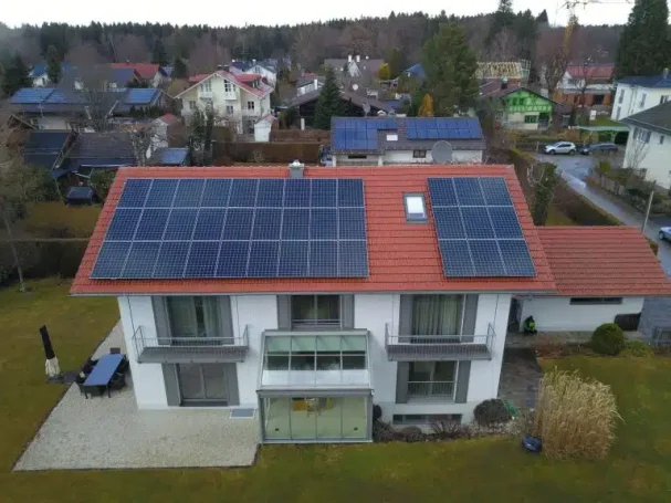 Zweifamilienhaus mit Solarpanelen auf dem Dach und grüner Haustür.