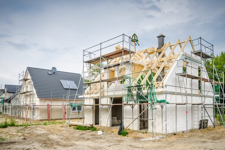 Bau eines Einfamilienhauses mit Gerüst und Dacharbeiten in einer Wohngegend.