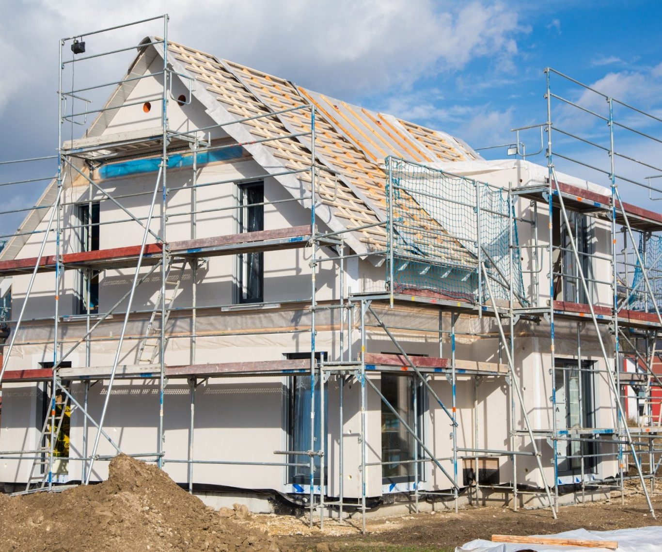 Baustelle eines Hauses mit Gerüst, unvollständigem Dach und frischem Putz.
