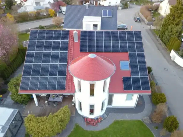 Haus mit rotem Dach und Solarpanelen auf einer modernen Architektur.