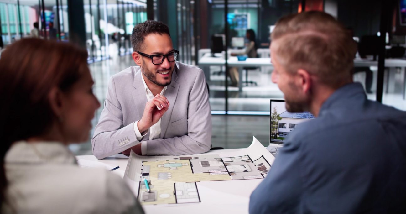 Drei Personen in einem modernen Büro diskutieren über Pläne und Ideen.