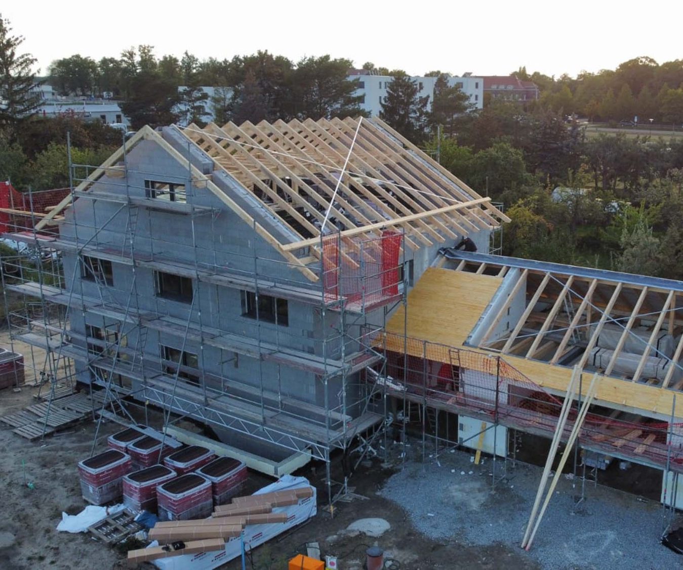 Bau eines Hauses mit Gerüst, unfertigem Dach und Baustellenmaterialien.