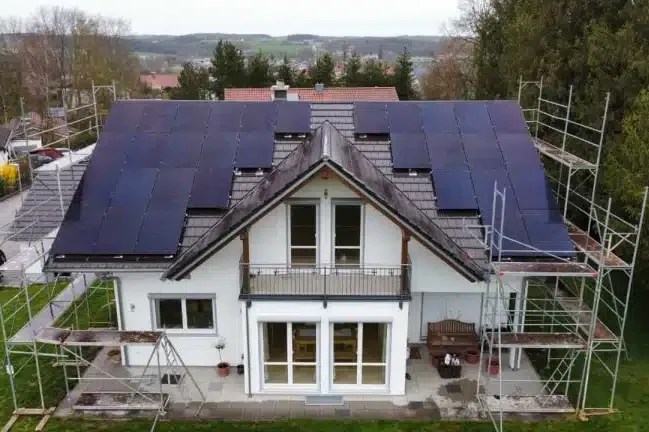 Moderne Villa mit Solarpanels auf dem Dach und Baugerüst rundherum.