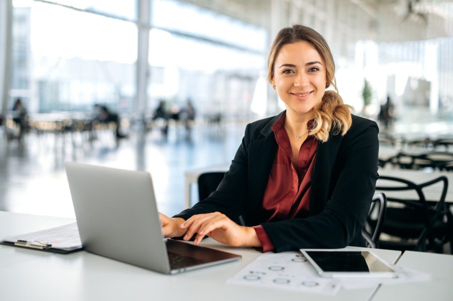 Frau im Business-Anzug arbeitet an einem Laptop in einem modernen Büro.