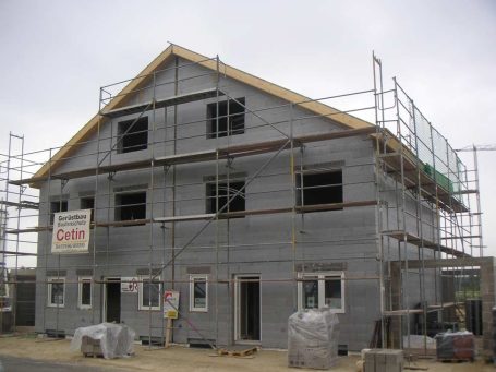 Neues Gebäude im Bau mit Gerüst und offenen Fenstern.