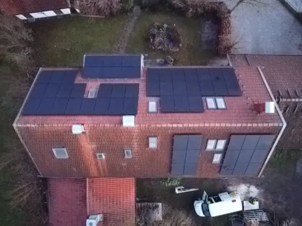 Dachansicht eines Hauses mit Solarpanelen und einem Fahrzeug im Vordergrund.