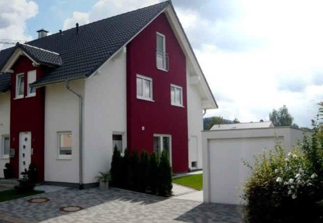 Moderne zweigeschossige Wohnung mit roter und weißer Fassade und angrenzendem Garten.